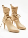 Pair of beige leather ankle boots with high heels on white background.